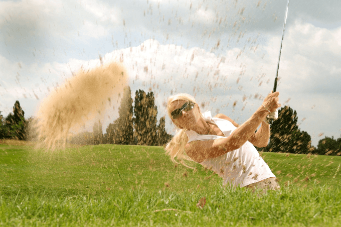 Golfer hitting ball in sand pit